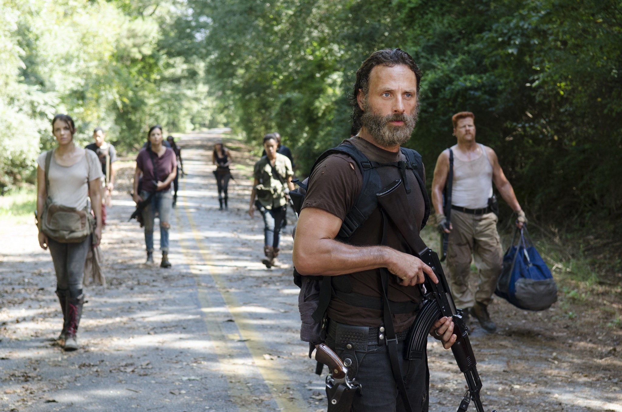 Image de la saison 5 ave Rick, Abraham, Sasha, Maggie, Tara et son groupe qui marche sur une route